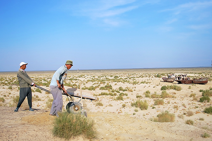 Robotnicy na tle kutrów i dna Morza Aralskiego – Moynaq (Uzbekistan)