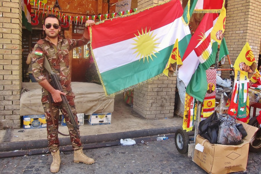Kurdish soldier in Erbil posing with a flag of Kurdistan.